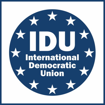 Ein fiktives Logo für die Internationale Demokratische Union: Blauer Kreis mit weißen Sternen am Rand und innen dem Text "IDU International Democratic Union".